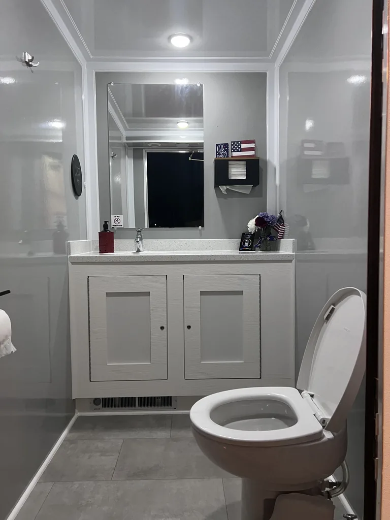 Women's restroom suite interior with quartz vanity, framed mirror and porcelain toilet